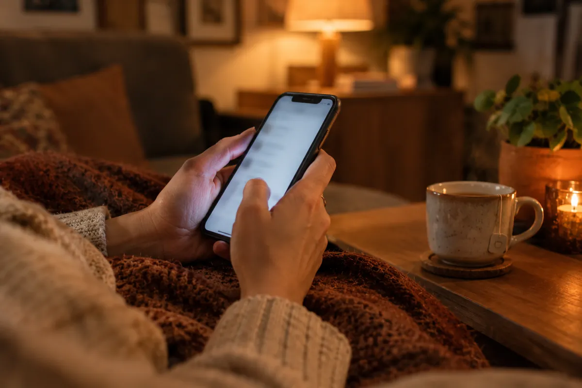 Iemand boekt thuis op de bank een afspraak op een telefoon